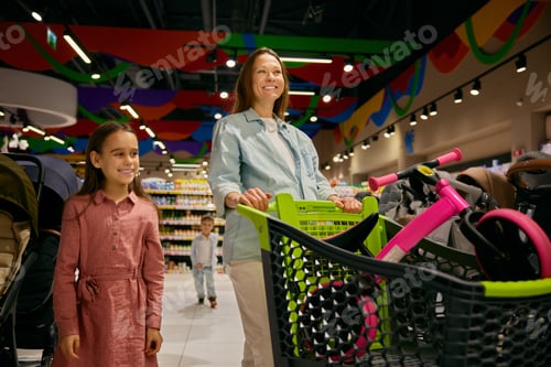 Preview: Positive pregnant mother and daughter doing purchases at toys store department
