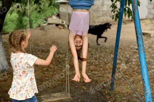 Preview: Girls ride a swing in the yard