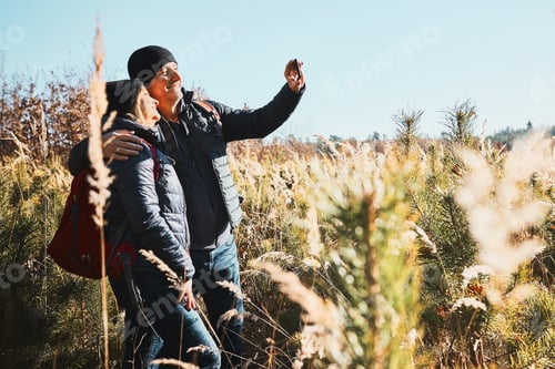 Preview: Hugging couple taking selfie while vacation trip. Hikers with backpacks on way to mountains