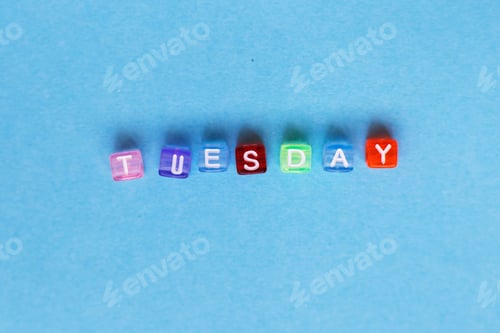 Preview: inscription Tuesday made by multicolor plastic cubes on a blue background.