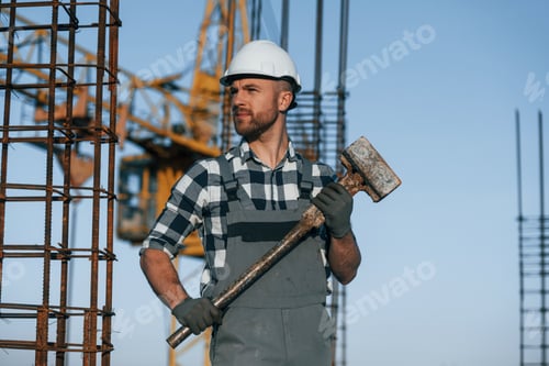 Preview: With big hammer in hands. Man is working on the construction site at daytime