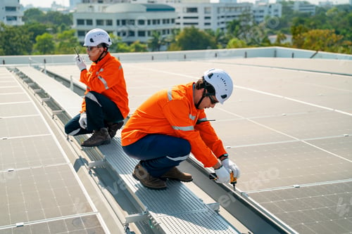 Preview: Workers install solar panels on a building rooftop in a sunny environment