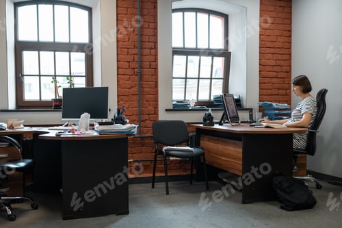 Preview: Pregnant woman working alone in half-empty office.