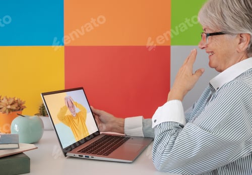 Preview: Elderly woman amused video chatting with a friend by laptop. Mature woman laughing