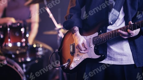 Preview: KYIV, UKRAINE - DECEMBER 30, 2021: cropped view of tattooed guitarist playing on stage