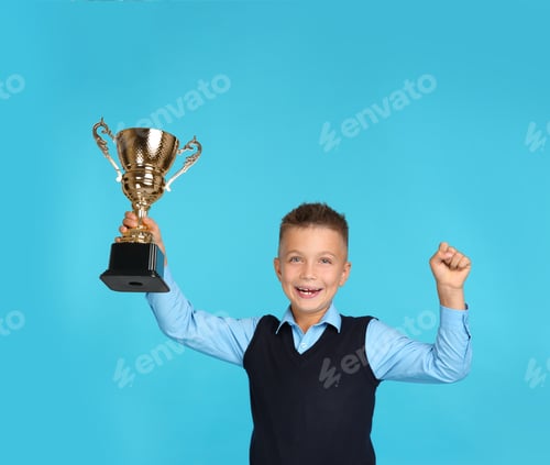 Preview: Happy boy in school uniform with golden winning cup on blue background