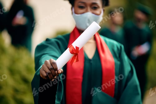 Preview: Close-up of Black student holding diploma on her graduation day during COVID-19 pandemic.
