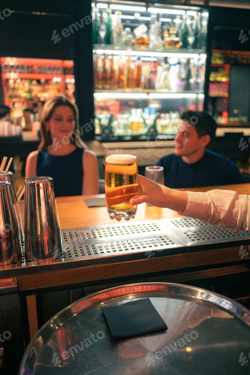 Preview: Bartender serving a glass of beer in a busy nightclub