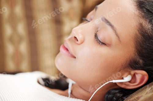 Preview: Music me time bliss. Shot of a young woman using earbuds while relaxing on the sofa at home.