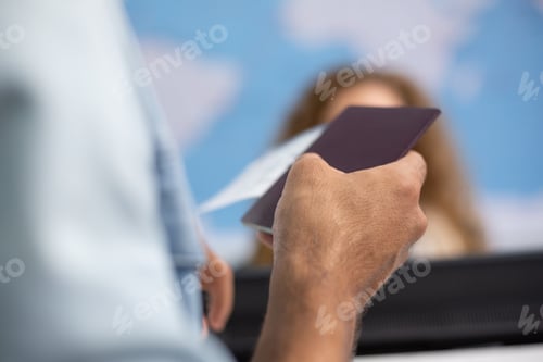 Preview: Hand of tourist passenger holding passport at the check in counter airport.