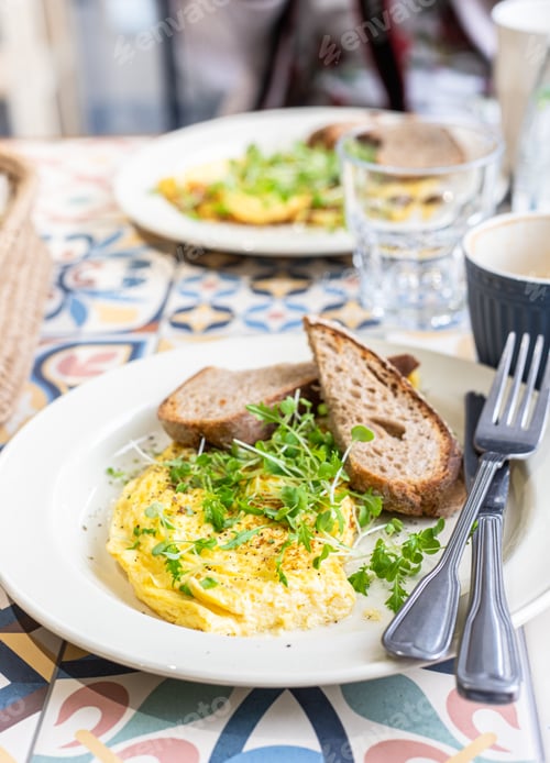 Preview: Omelette served with micro green and toasted bread on ceramic plate.
