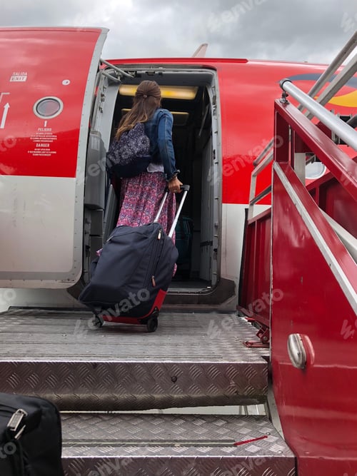 Preview: Traveling woman from behind at the airport boarding her airplane with luggage carry-on