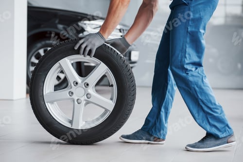 Preview: Mechanic holding a tire tire at the repair garage. replacement of winter and summer tires