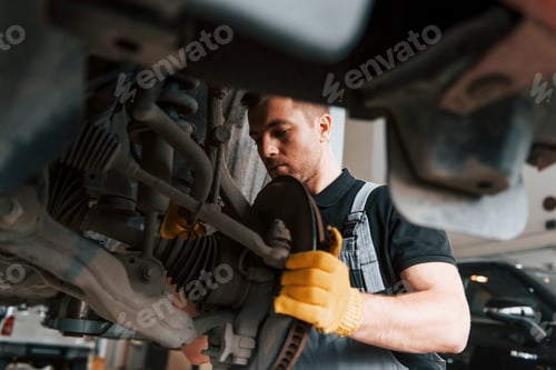 Preview: Professional service. Man in uniform is working in the auto service