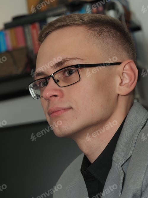 Preview: Portrait of a young man of European appearance in a business suit and glasses.