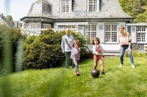 Preview: Happy extended family playing football in garden