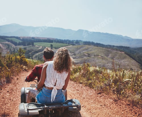 Preview: Young couple riding on a quad bike in countryside