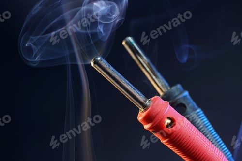 Preview: Closeup shot of red and black banana plug connectors on background of smoke