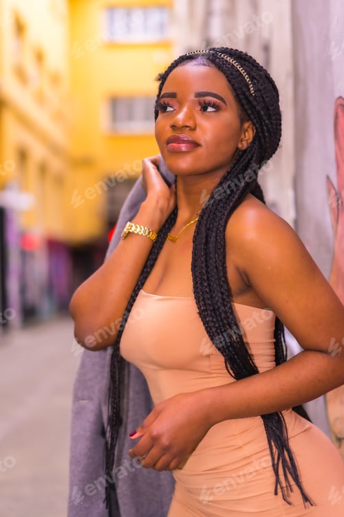 Preview: Trendy urban style with a black African girl in a cream colored dress on a city street