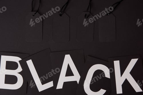 Preview: top view of blank price tags and black lettering on black surface, black friday concept