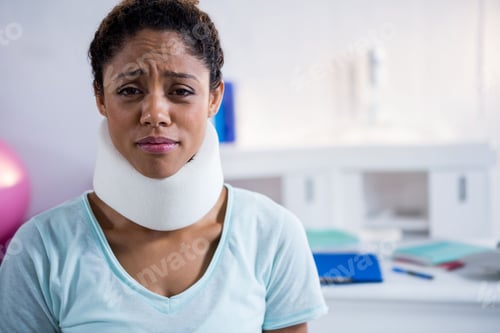 Preview: African American woman sitting in therapy room wearing cervical collar and reaching for blue binder