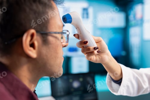 Preview: Healthcare expert uses a digital thermometer to check for fever and flu symptoms
