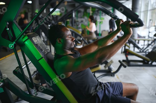 Preview: Motivated young black sportsman having workout on rowing machine