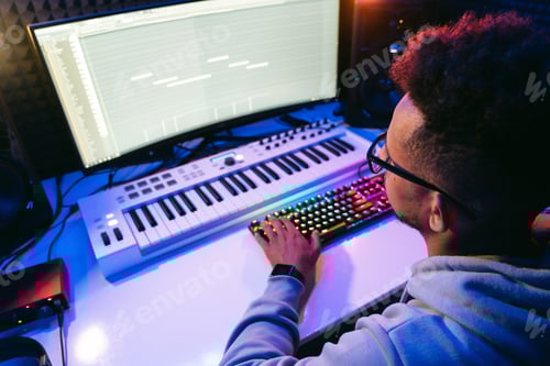 Preview: Sound producer working in a technological modern studio with lights on dark background