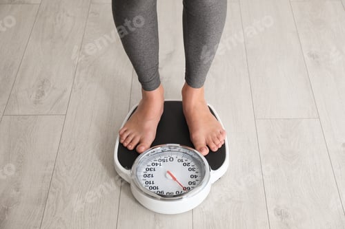 Preview: Woman standing on scales indoors. Overweight problem
