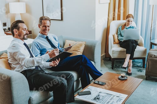 Preview: Meeting At Hotel. Cheerful Friendly Middle Aged Businessmen In Elegant Clothes Sitting On The Sofa