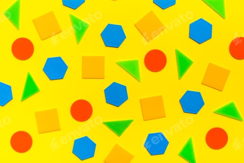 Preview: Various flat figures - circles, triangles, squares, hexagons - lie abstractly on yellow cardboard.