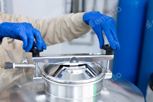 Preview: a male worker opens the metal barrel in the factory