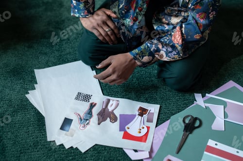 Preview: Close-up of young creative man sitting by papers with self-made collages