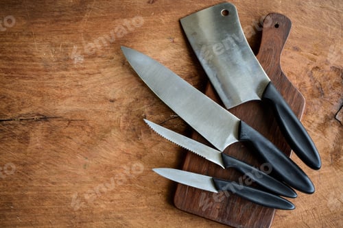 Preview: Set of kitchen knifes on wooden cutting board on old wooden table