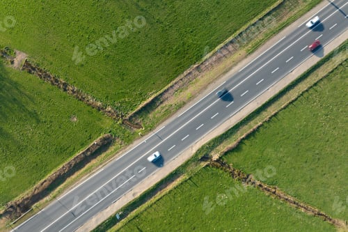 Preview: Aerial view of intercity road between green agricultural fields with fast driving cars.