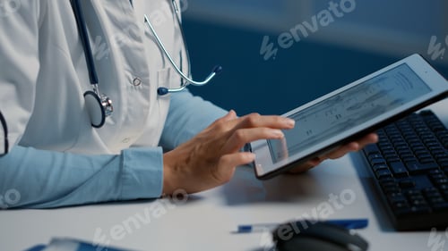 Preview: Close up of general practitioner holding tablet computer analyzing radiography