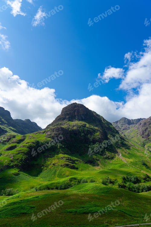 Preview: Lush green mountain under blue sky in Glencoe.