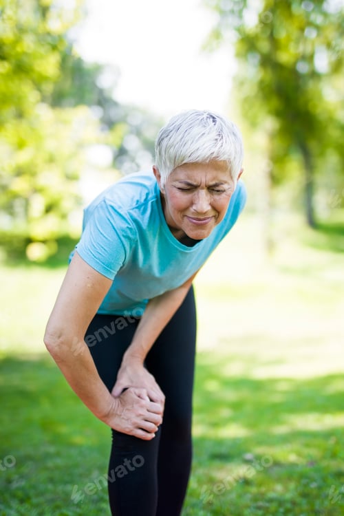 Preview: Senior sportswoman with knee pain standing in park
