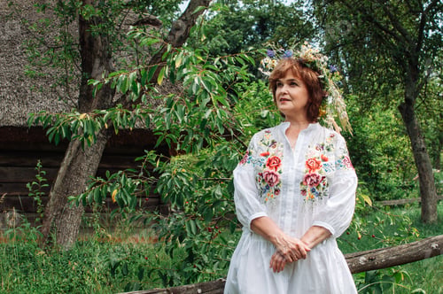 Preview: woman in Ukrainian dress with a wreath of wildflowers in the garden
