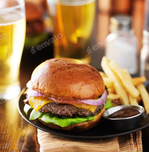 Preview: tasty cheeseburger and fries with beer at restaurant