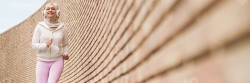 Preview: Middle eastern woman in hijab listening music with headphones and running