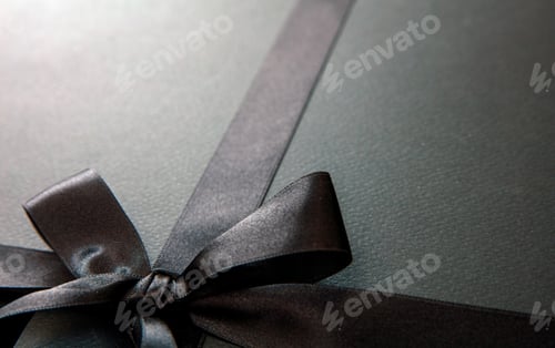 Preview: Black Friday Sale and Christmas gifts concept. Black satin ribbon and bow tied, close up