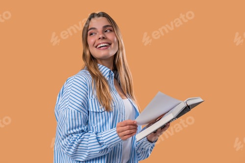 Preview: Young blonde woman reading book with focused smile on beige. Discovery time