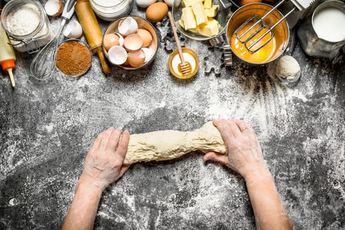 Preview: Dough background. Woman kneads dough with various ingredients on the table.