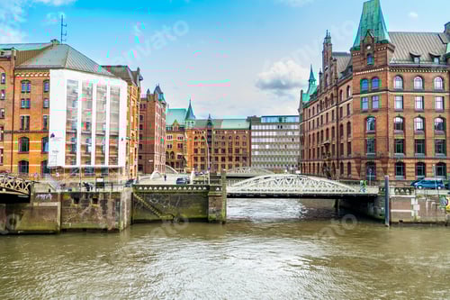 Preview: Cityscape of Hamburg showing a mix of architectural eras by the water.