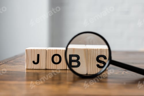 Preview: close-up shot of wooden blocks with JOBS sign and magnifying glass on table