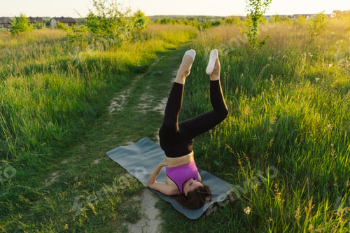 Preview: Beautiful girl doing fitness or yoga in nature on a sunny summer sunset.