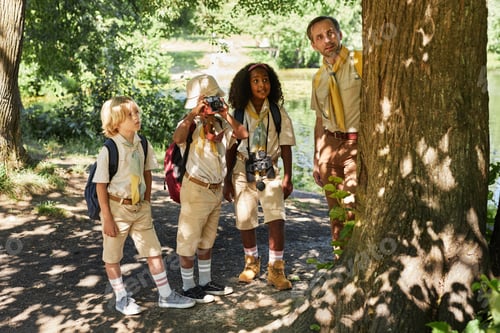Preview: Diverse group of little scouts in forest exploring nature
