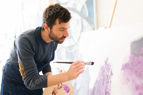 Preview: Good-looking painter doing some strokes on a canvas