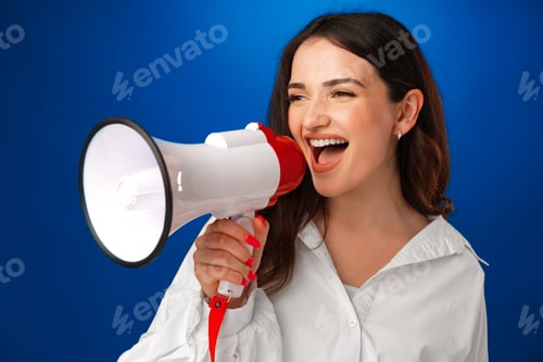 Preview: Young brunette businesswoman holding a megaphone against blue background